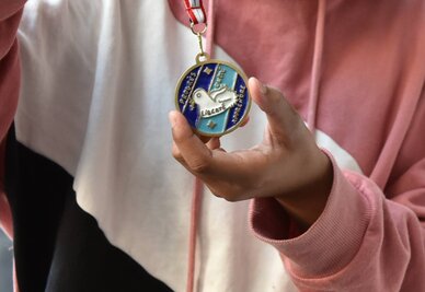La médaille créée par l'école Jules-Ferry représente un oiseau sur fond bleu, entouré des mentions : progrès, unité, liberté, apprendre
