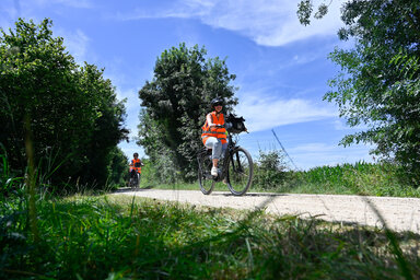 Deux cyclistes portant des gilets haute visibilité roulent sur un chemin rural lors de l'inauguration de l'itinéraire Vélideale