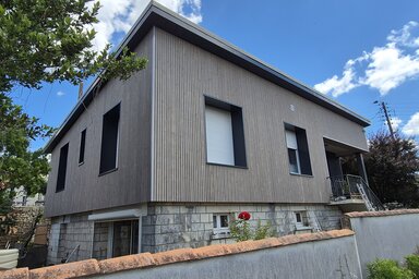 Maison individuelle rénovée avec isolation par l'extérieur, bardage gris posé sur la façade et nouveaux volets roulants