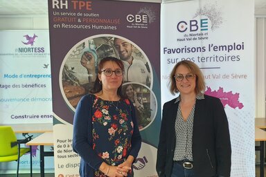 Deux femmes devant les roll-ups RH TPE et « Favorisons l'emploi sur nos territoires »