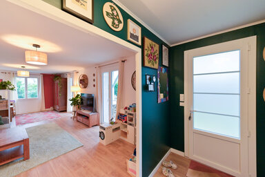 Entrée et salon d'un logement résidentiel aux murs vert foncé, parquet clair et décoration personnalisée